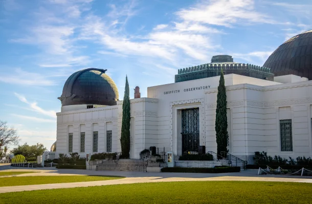 Griffith Observatory's iconic white Art Deco building with copper domes against blue sky in Los Angeles