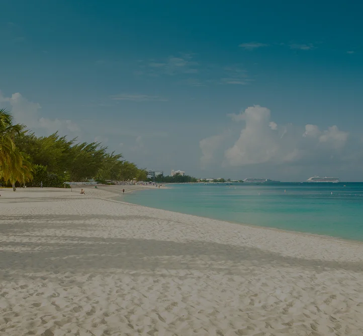 Pristine white sand beach with swaying palm trees and turquoise waters in Grand Cayman, Caribbean