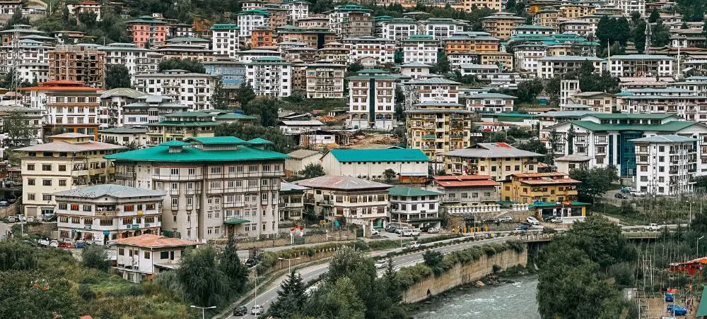 Colorful multi-story buildings cascade down hillsides in Thimphu, Bhutan's capital city and luxury travel destination