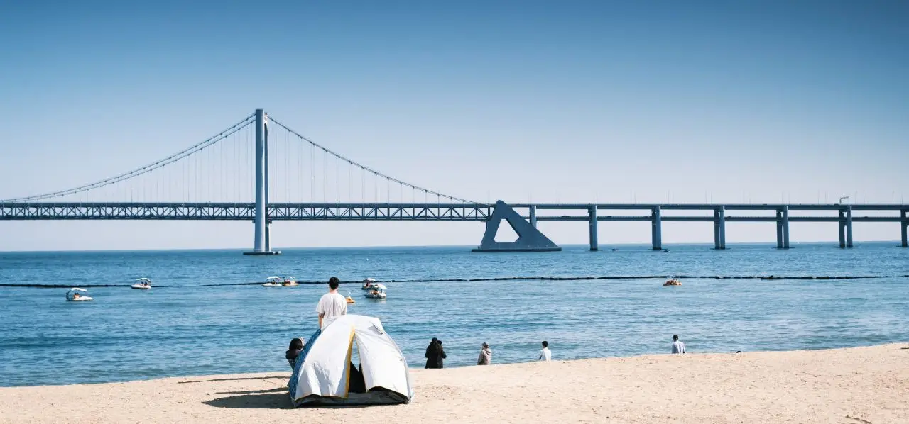Scenic Busan beach with iconic Gwangan Bridge spanning across calm blue waters under clear skies