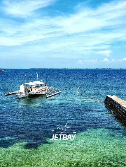 Crystal clear turquoise waters surround traditional Filipino outrigger boat near Cebu's pristine coastline
