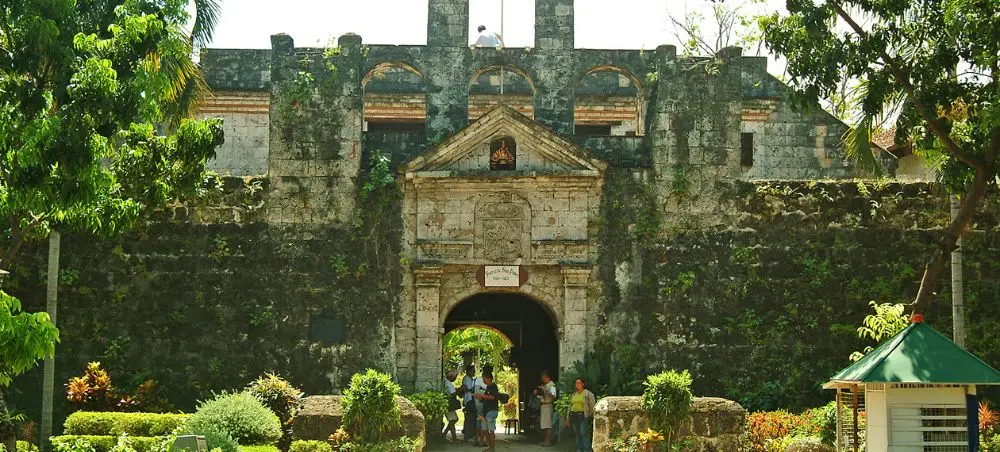 Historic Fort San Pedro entrance gate with stone walls and tropical gardens in Cebu City, Philippines