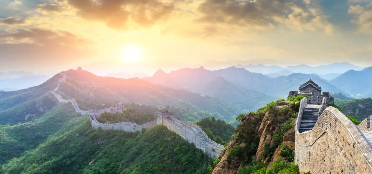 Great Wall of China winding through misty mountains at golden sunset, showcasing premier destination