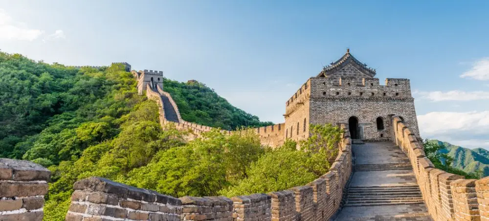 Great Wall of China winding through lush green mountains near Beijing, showcasing ancient stone architecture