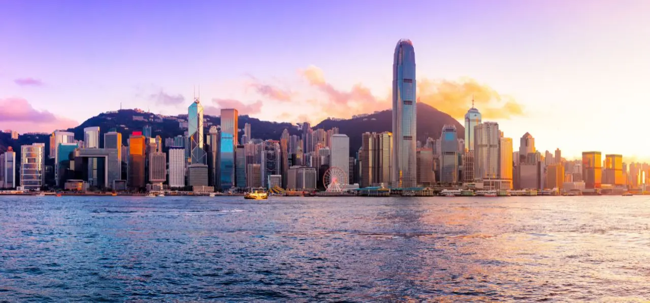 Hong Kong skyline at golden hour with Victoria Harbour waters reflecting the illuminated skyscrapers