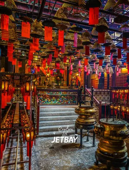 Traditional Hong Kong temple interior with red lanterns, incense coils, and ornate bronze vessels