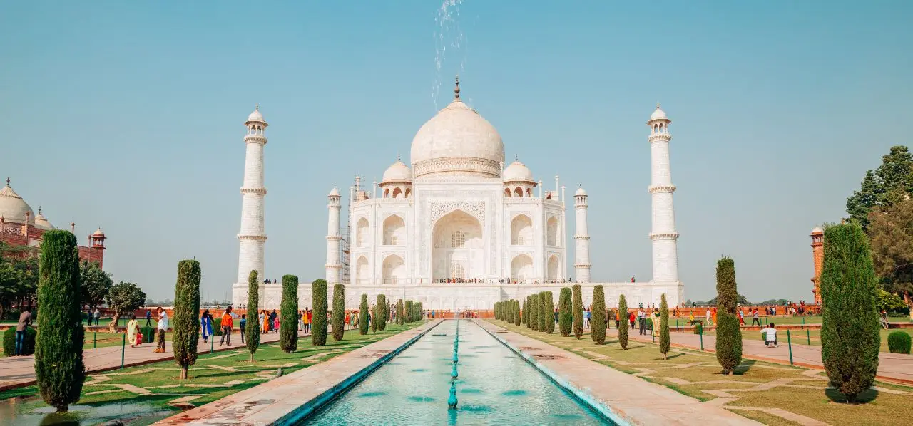 Taj Mahal's iconic white marble dome and minarets reflected in ornamental pools, showcasing India's architectural heritage