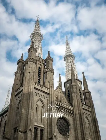 Gothic cathedral spires reaching toward cloudy sky in Jakarta, showcasing Indonesia's colonial architectural heritage