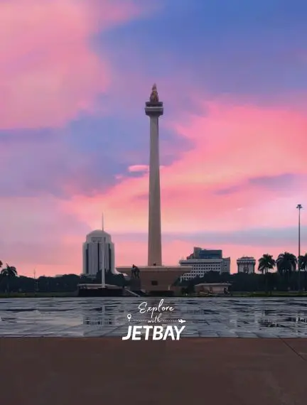 Jakarta's iconic Monas tower stands tall against vibrant sunset skies in Indonesia's bustling capital city