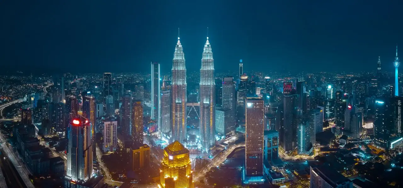 Kuala Lumpur skyline at night featuring illuminated Petronas Twin Towers and modern skyscrapers