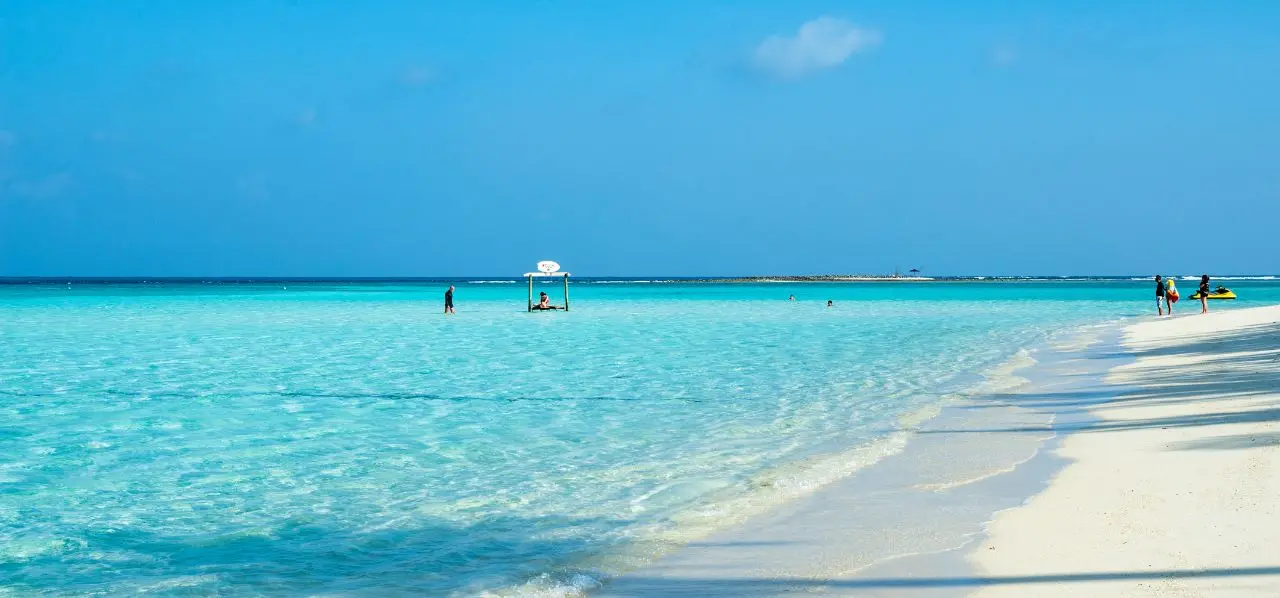Pristine turquoise waters and white sand beach in Male, Maldives with visitors enjoying luxury tropical paradise