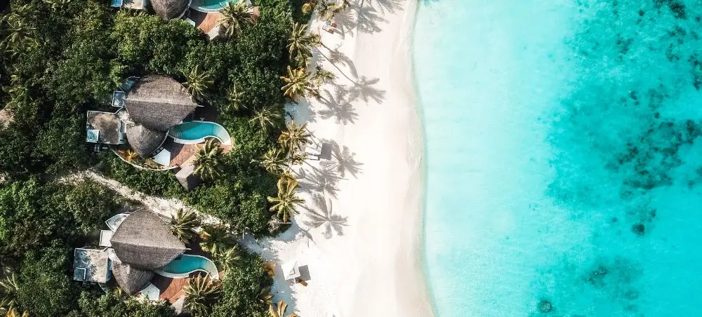 Aerial view of luxury overwater villas with private pools and pristine turquoise lagoon in the Maldives