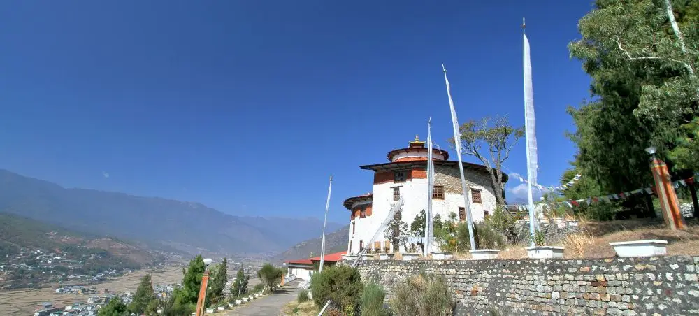Traditional Bhutanese fortress architecture in Paro valley with prayer flags and mountain backdrop