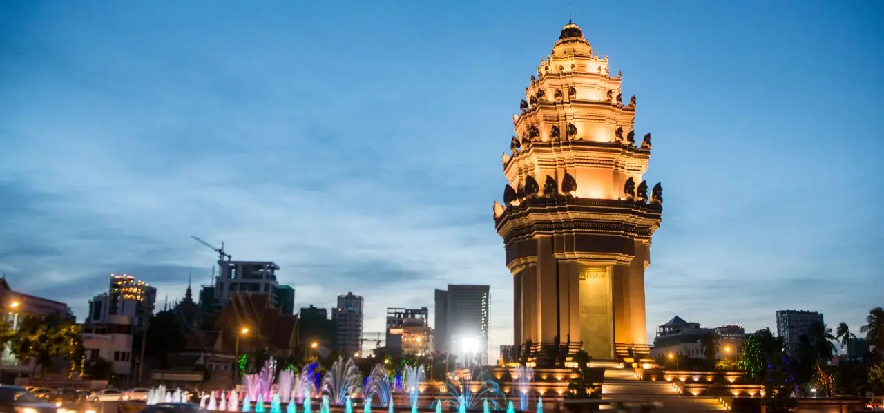 Independence Monument illuminated at dusk with colorful fountains in Phnom Penh's city center