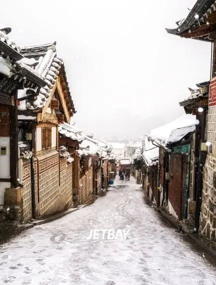 Snow-covered traditional Korean hanok houses line historic Bukchon village street in Seoul winter