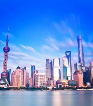 Shanghai skyline featuring Oriental Pearl Tower and modern skyscrapers reflecting in Huangpu River at dusk