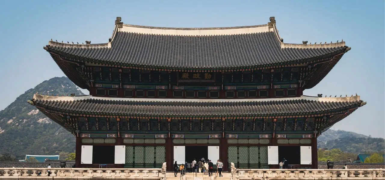 Traditional Korean palace architecture with ornate curved rooflines and mountains, showcasing Seoul's cultural heritage