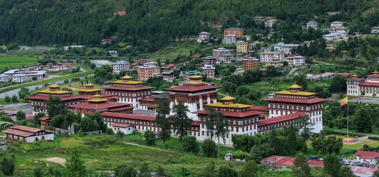 Panoramic view of Thimphu's traditional dzong fortress and modern buildings nestled in Bhutan's green valley