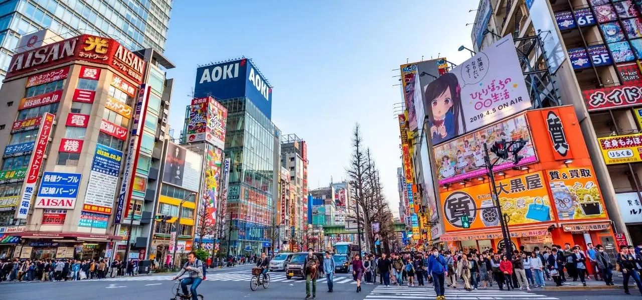 Bustling Tokyo street scene with vibrant neon signs, crowds crossing at famous Shibuya intersection