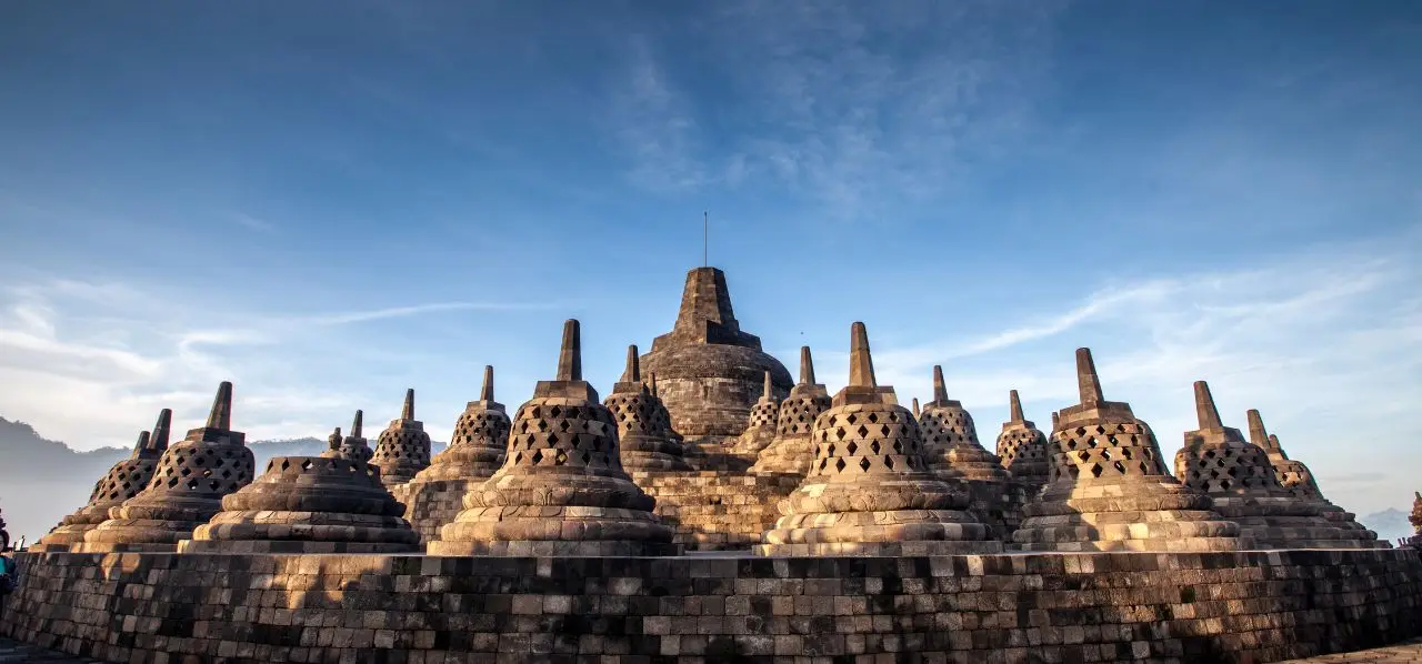 Ancient Borobudur temple complex with ornate stone stupas against blue sky in Yogyakarta, Indonesia