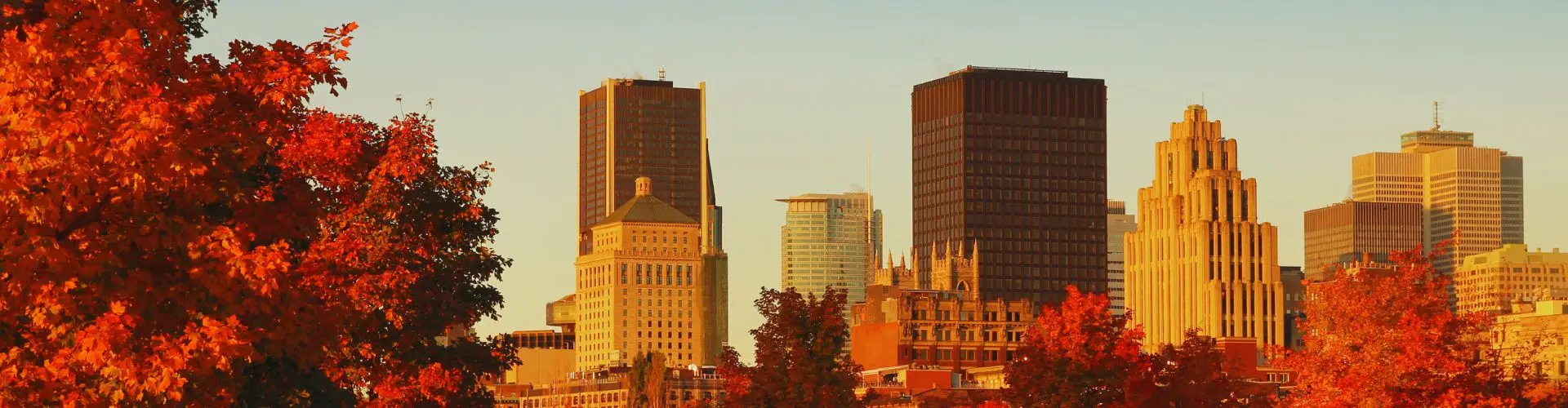 Private Jet Charter from Montréal–Trudeau International Airport Montreal skyline with autumn foliage framing downtown buildings during golden hour sunset