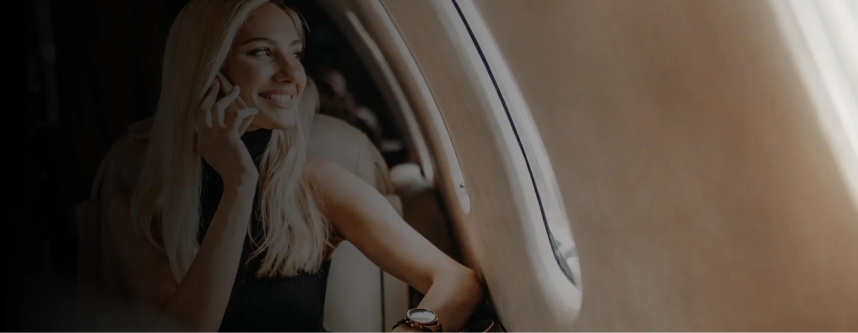 Smiling passenger taking a phone call while seated in a private jet cabin